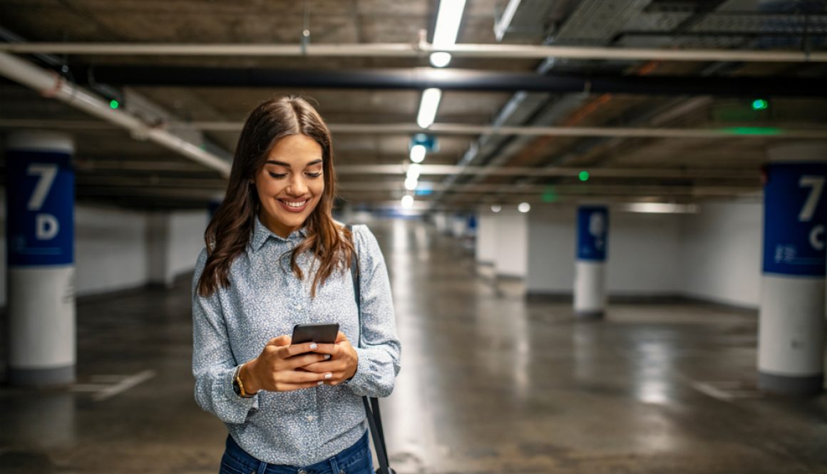 Businesswoman,In,Underground,Garage.,Elegant,Woman,Using,Smartphone,In,Parking