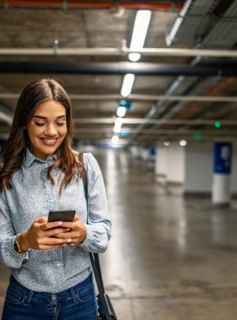 Businesswoman,In,Underground,Garage.,Elegant,Woman,Using,Smartphone,In,Parking