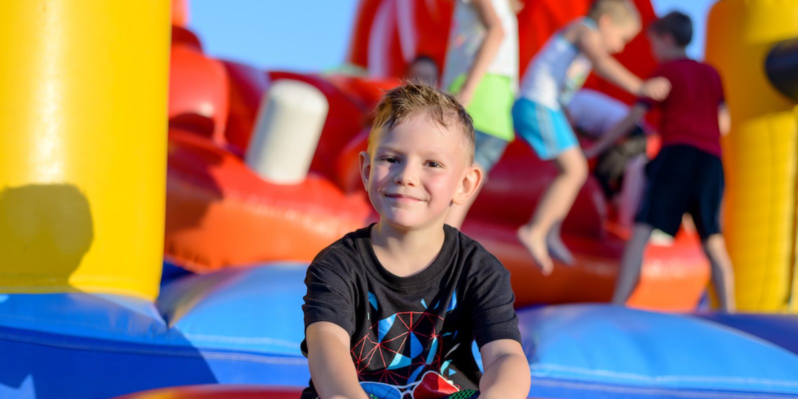 Smiling little boy sitting on a jumping castle